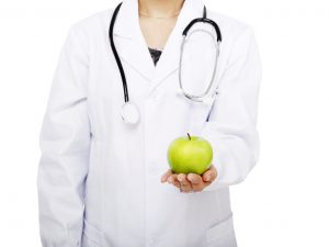 The,Young,Female,Doctor,Holding,A,Green,Apple